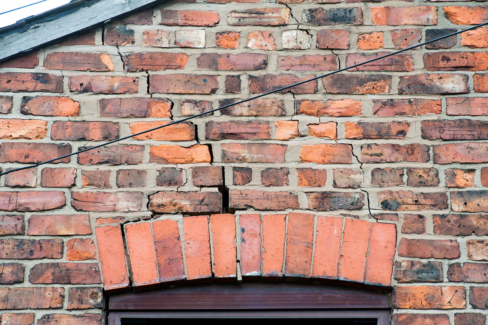 step cracking damage to brickwork in a wall above a window as a