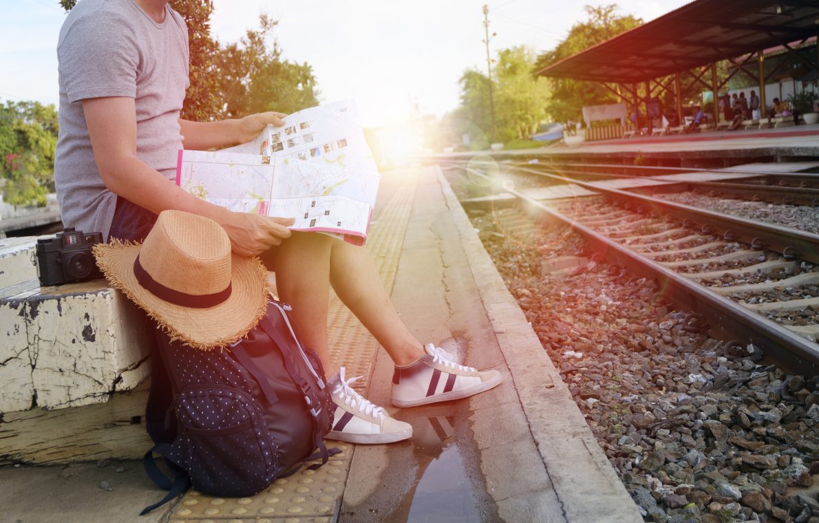 young man traveler with backpack and hat at the train station with a traveler , travel and recreation concept